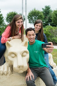 Three students at Penn State Harrisburg take a selfie with the Nittany Lion Shrine.